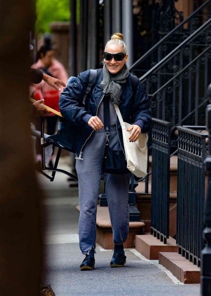 Look of the Day for April 29, 2024 features Sarah Jessica Parker in comfy sweatpants, matching top, black bomber jacket, multiple handbags, and those comfy black clogs she’s worn for decades.