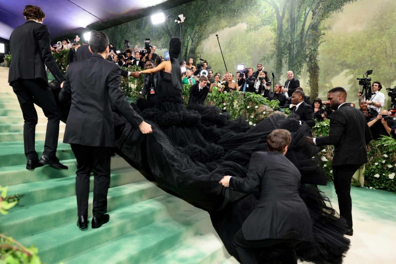 Cardi B's 2024 Met Gala dress was a gothic glam creation designed by Windowsen. The dramatic tulle gown, which featured almost 10,000 feat of fabric, covered the entire Met Gala staircase and needed its own team to carry the skirt. Designer Sensen Lii said he was inspired by the event's "Garden of Time" dress code.